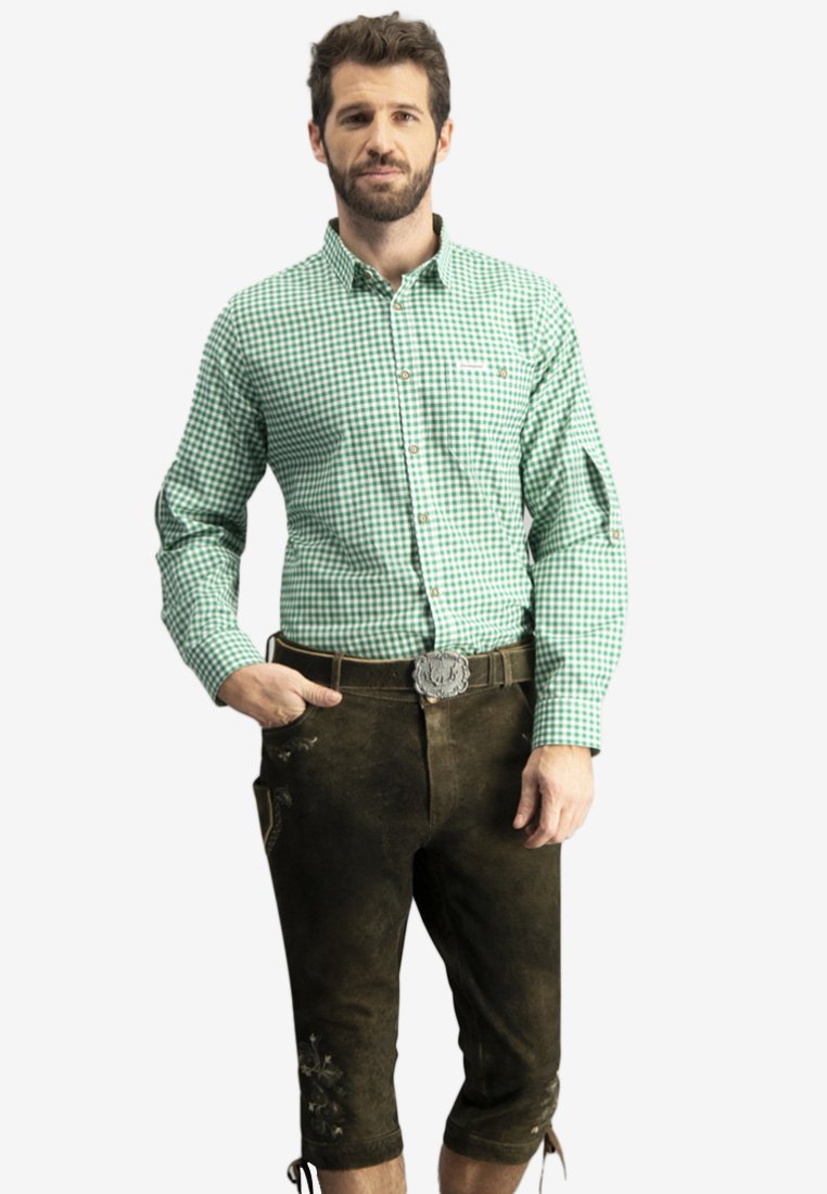 Grünes und weißes Karohemd mit tailliertem Schnitt, kombiniert mit dunkelbraunen Lederhosen, die mit gestickten Blumenmotiven und einer silbernen Gürtelschnalle verziert sind.