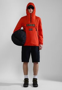 Feloranje, hooded jack met een rits en een voorzak; zwart logo patch en Noorse vlag. Draag het met zwarte shorts en stevige laarzen.