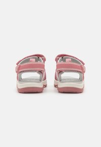 Pink sandals with open backs, adjustable straps, textured fabric, and cushioned soles. Features a lightweight design and durable grip.