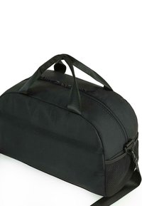 Bolso de viaje negro con una textura suave y mate; presenta dos asas y un cierre de cremallera; incluye un acento de malla para ventilación.