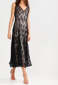 Svart spets midi klänning med blommönster, V-ringning och spaghettistraps, som har en lös passform och genomskinliga lager.