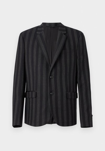 Fekete csíkos zakó, hajtott gallérral, két elülső zsebbel és egygombos záródással. Az anyaga sima tapintású, enyhe fényességgel.