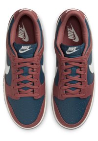 Nike-sneakers med en mörkblå läderskaft, vinröda detaljer, perforerat tånät, vit swoosh och matchande snördesign.