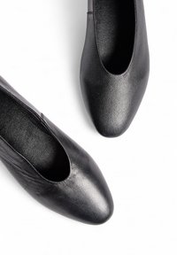 Zwarte leren ballerina's met een ronde neus en een gladde textuur. Heeft een lage uitsnijding aan de zijkanten voor gemakkelijk aan- en uittrekken.