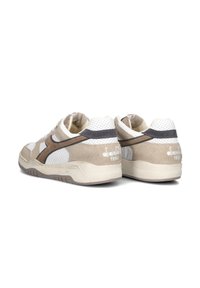 Sneakers beige e crema realizzati in pelle e camoscio, con dettagli perforati, accentuazioni grigie e branding bianco sul tallone e sul lato.