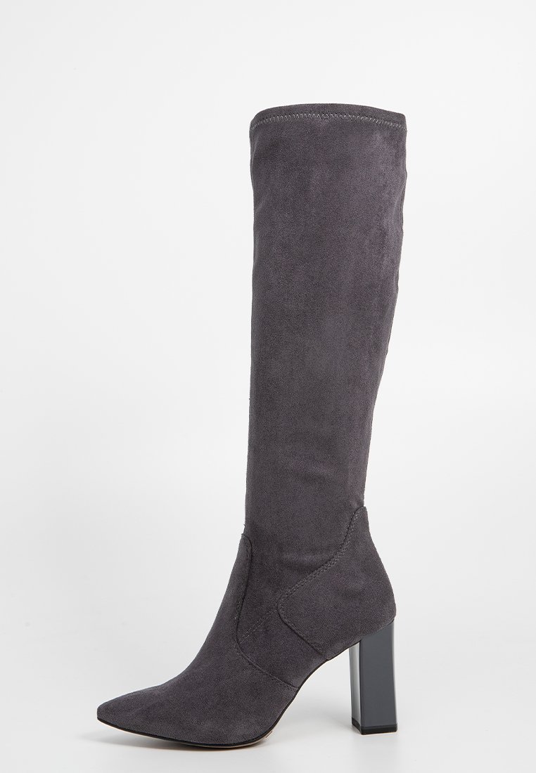 Stivale grigio in suede alto fino al ginocchio, con punta affilata e tacco quadrato. Presenta cuciture sottili e una trama morbida e liscia.