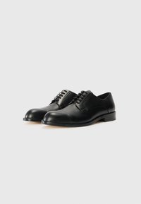 Black leather dress shoes with a smooth finish, round toe, and lacing system. Features a subtle cap toe detail and low, sturdy heel.
