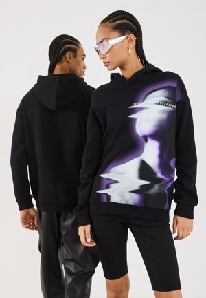 Black hoodie with a front graphic in purple and white depicting a distorted face. Features a kangaroo pocket and ribbed cuffs.