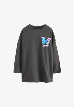 Dunkelgraues, übergroßes T-Shirt mit dreiviertel Ärmeln, das ein buntes Schmetterlingsmotiv und den Text "GUTE TAGEN STEHEN IMMER BEVOR" zeigt.