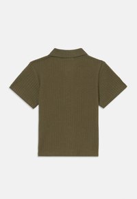 Polo verde-oliva com um design texturizado em malha aberta. Apresenta um colarinho clássico e mangas curtas, destacando um estilo respirável.
