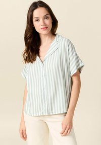 Blusa a maniche corte con colletto in verde chiaro e bianco a righe verticali, con chiusura a bottoni e silhouette rilassata. Tessuto morbido.