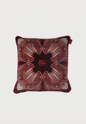 Square cushion with intricate red, maroon, and white paisley patterns and a central winged lion motif on dark background.
