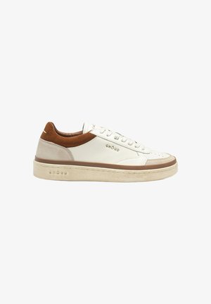 Sneaker bianca low-top con tacco in suede marrone e suola beige, con lacci frontali e logo "GHOUD" sul lato e sulla suola.