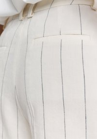 Beige broek met verticale blauwe strepen, op maat gemaakt ontwerp met een gladde textuur en achterzakdetails.