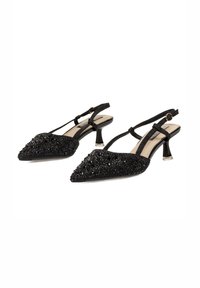 Zapatos de tacón negro con tiras, punta afilada, adornados con lentejuelas negras, con un tacón bajo y transparente de lucite y correa ajustable.