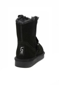 Botines de ante negro con un interior suave y esponjoso, que cuentan con un parche de logo y cremallera lateral. La suela es plana y texturizada para un mejor agarre.