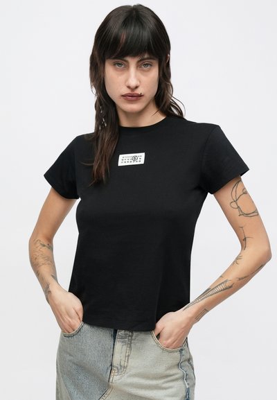 Zwart katoenen T-shirt met korte mouwen, voorzien van een wit labelontwerp op de borst. Gladde textuur en een reguliere pasvorm, minimalistische stijl.