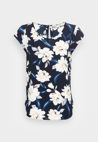 Top floral azul-marinho com mangas curtas em forma de capinha, apresentando grandes flores brancas e rosa suave, folhas verdes, e um decote arredondado com um detalhe de abertura nas costas.