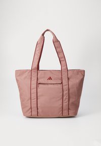 Bolsa tote de nylon rosa con dos asas anchas, que presenta un bolsillo frontal con cremallera y un logo en relieve. Textura suave con costuras reforzadas.