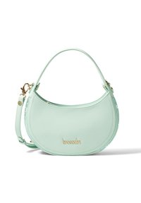 Mintgrüne Lederhandtasche mit geschwungener Form, goldener Hardware und abnehmbarem Tragegurt. Auffälliges Markenlogo auf der Vorderseite.