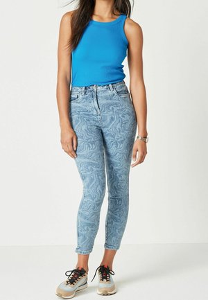 Blue tank top paired with light blue patterned skinny jeans and multicolored sneakers, showcasing a fitted design and subtle texture details.