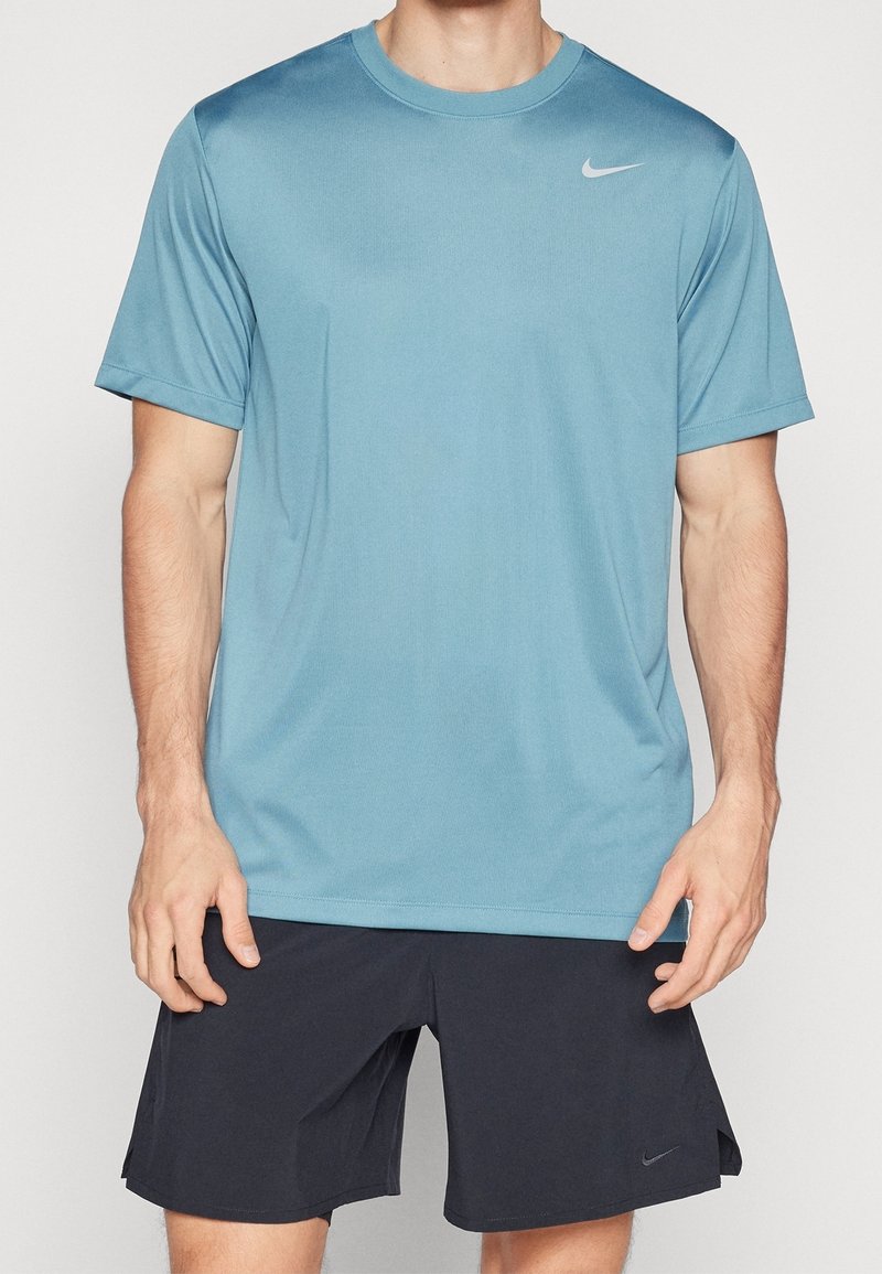 Nike kurzärmliges Sportshirt in Hellblau, aus glattem Stoff, mit Rundhalsausschnitt und einem kleinen silbernen Logo oben links.