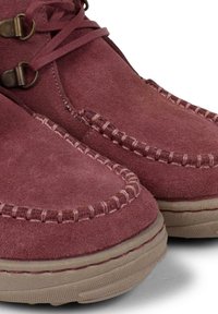 Stivali alla caviglia in camoscio bordeaux con cuciture decorative, punta tonda e suole in gomma beige con finitura testurizzata. Include lacci regolabili.