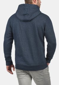 Hættetrøje i marineblå med et tekstureret stof, ribbede manchetter og kant, med en glat finish og en hætte med snor.