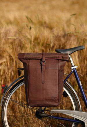 Ruda odinė dviračio kuprinė su ritininio uždarymo sistema, reguliuojama petneša ir perforuotais akcentais; pritvirtinta prie mėlynos dviračio rėmo.