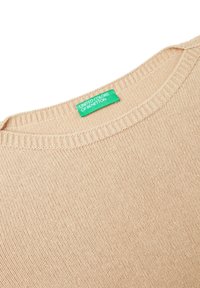 Beige gestrickter Pullover mit Rippenkragen und einem grünen Etikett mit der Aufschrift "United Colors of Benetton" auf der Rückseite.