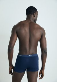 Herren Boxershorts in marineblau aus weichem Stoff, mit einem elastischen Bund, auf dem der Markenname "GANT" in Weiß gedruckt ist.