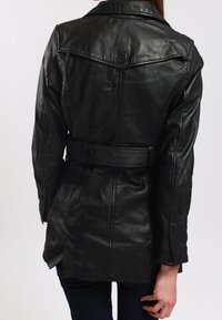 Černá kožená bunda s páskem v pase, vykrojeným límcem a švy na ramenou. Texturovaný povrch, přiléhavý design s bočními rozparky.