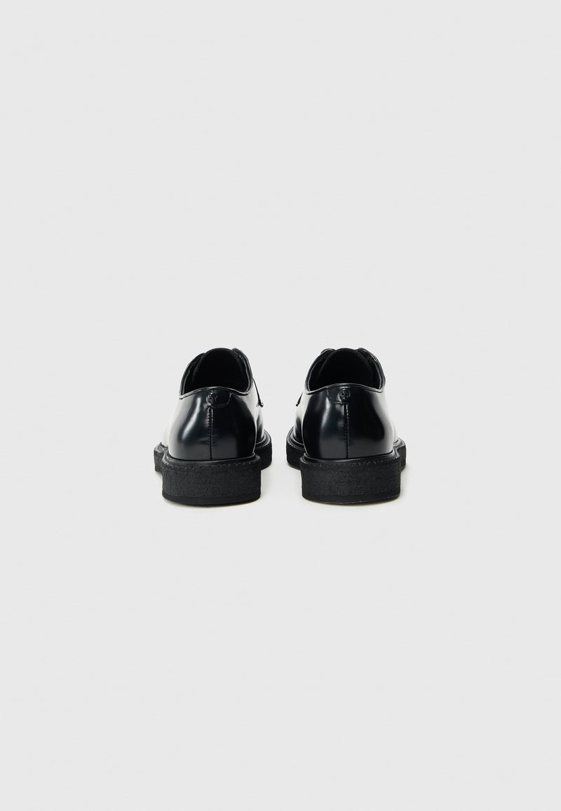 Black patent leather shoes with a rounded toe and textured rubber sole, featuring a smooth finish and minimalistic design.