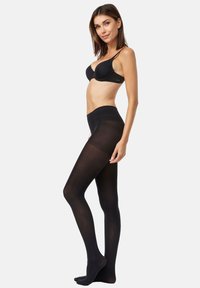 Sort uigennemsigtige strømpebukser med en glat tekstur, der har en høj talje. Modellen poserer fra siden og fremviser benlængden og pasformen.