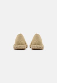 Beige stof espadrilles med rundede tæer, syet kant og flettede jutesåler. Designet er minimalistisk uden synlige logoer.