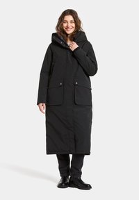 Zwarte lange jas met een capuchon, voorzien van een ritssluiting en drukknoopsluiting, twee grote voorzakken en een gladde, matte textuur.