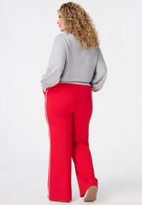 Gray cropped sweatshirt with long sleeves, paired with red wide-leg pants featuring white side stripes. Smooth texture and casual design.