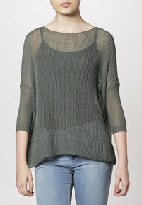 Suéter de punto acanalado de corte holgado en verde oscuro, con mangas tres cuartos, un escote amplio y una textura ligeramente transparente.