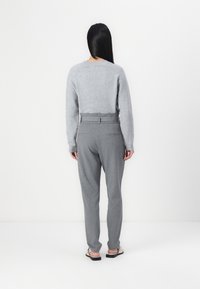Pull en laine gris avec des poignets côtelés et un col ras du cou, associé à un pantalon gris ajusté avec une ceinture et des poches latérales. Vue de dos complète.
