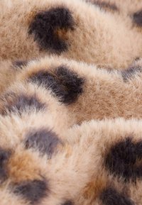 Mäkká béžová a hnedá leopardia potlač z kožušiny s nadýchanou textúrou a nepravidelnými tmavými škvrnami v detailnom zábere.