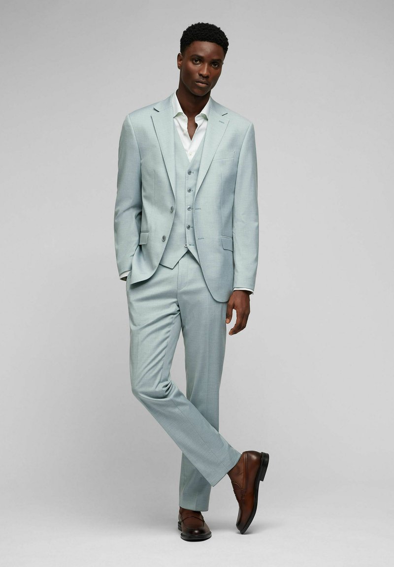 Hellesblaues Dreiteiliges Anzugset in schlanker Passform, bestehend aus Blazer, Weste und Hose. Braune Lederschuhe runden den Look ab.