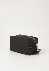 Borsa cosmetica rettangolare nera realizzata in tessuto testurizzato, con una zip argento e dettagli di cucitura bianca.