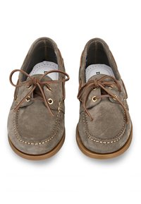 Scarpe da barca in suede marrone con punta rotonda, lacci in pelle e occhielli in ottone. Dettagli cuciti e suola in gomma per una maggiore trazione.