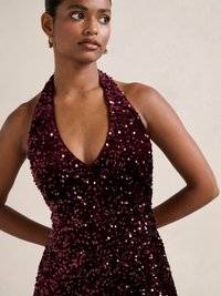 Burgundy sequined halter dress with a V-neckline. Features a fitted silhouette and a shiny, reflective texture.