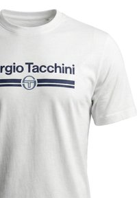Hvit t-skjorte med korte ermer med mørkeblå "Sergio Tacchini"-tekst og logo, med to horisontale striper under merkenavnet.