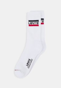 Chaussettes en coton blanches avec des accents de logo Levi's rouge et noir. Présentent une texture côtelée et une zone de renfort au niveau des orteils pour plus de durabilité.