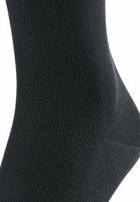 Calzino nero a coste realizzato in un materiale elasticizzato. Presenta un tallone e una punta rinforzati, con una texture liscia e una vestibilità aderente.