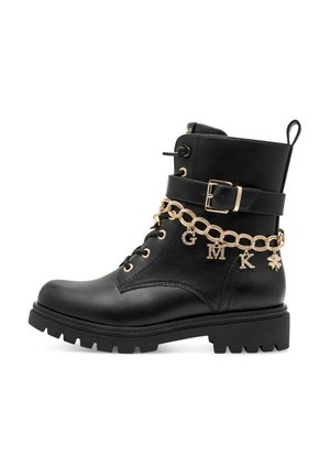 Botte de combat en cuir noir avec sangle à boucle dorée et chaîne décorative dorée avec breloques lettres G, M, K et un trèfle.