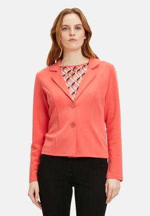Blazer corallo con maniche lunghe e colletto a risvolto, dotato di due bottoni e una vestibilità strutturata. La camicia interna presenta un motivo geometrico.