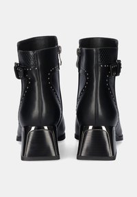 Botas de tobillo de cuero negro con un acabado texturizado, detalles de tachuelas, cremallera lateral y tacones metálicos gruesos.